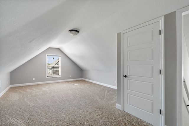 additional living space with a textured ceiling, carpet flooring, and vaulted ceiling