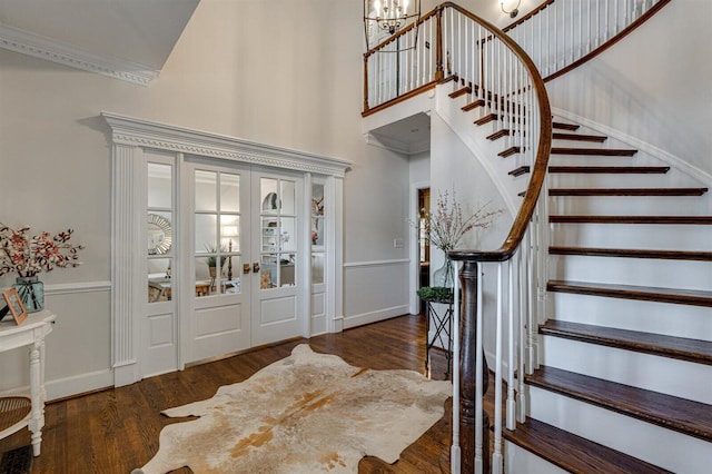 foyer with a high ceiling, ornamental molding, dark hardwood / wood-style floors, and french doors