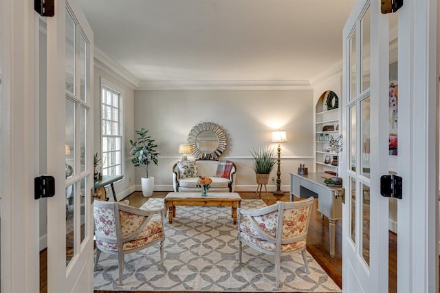 sitting room with french doors, crown molding, built in shelves, and hardwood / wood-style flooring