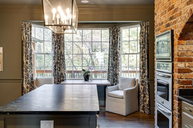 dining area featuring crown molding, brick wall, dark hardwood / wood-style floors, and a chandelier