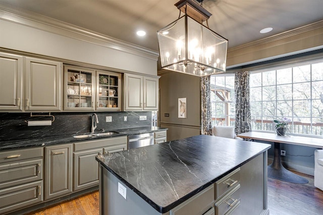 kitchen featuring sink, stainless steel dishwasher, ornamental molding, a kitchen island, and pendant lighting