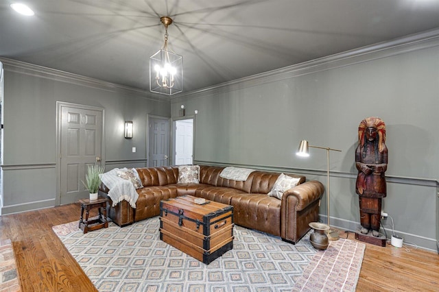 living room featuring wood-type flooring, a notable chandelier, and crown molding