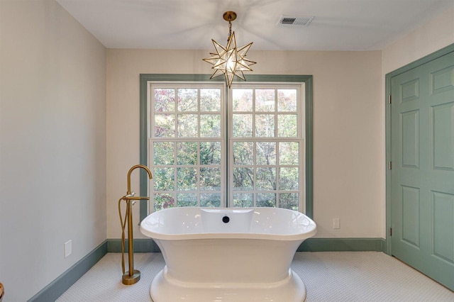 bathroom featuring a notable chandelier and a tub