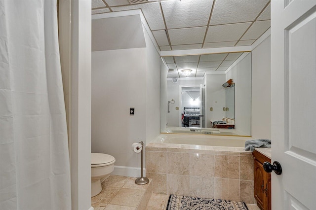 bathroom featuring tile patterned flooring, a paneled ceiling, a bathtub, and toilet