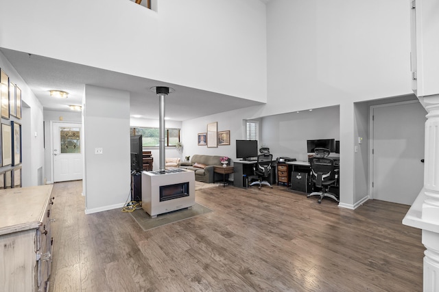 home office featuring a towering ceiling, heating unit, and dark hardwood / wood-style floors