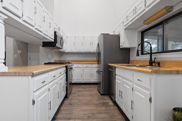 kitchen featuring butcher block counters, dark hardwood / wood-style floors, sink, white cabinets, and appliances with stainless steel finishes