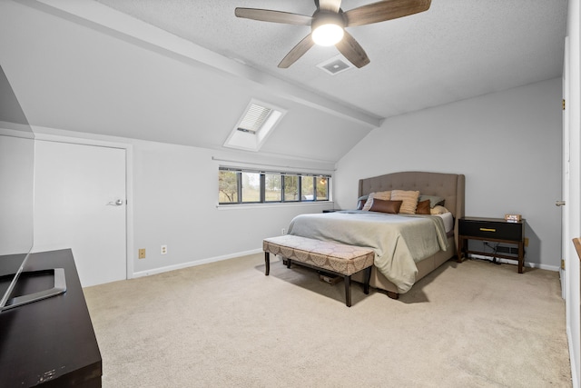 bedroom with ceiling fan, vaulted ceiling with skylight, a textured ceiling, and light colored carpet