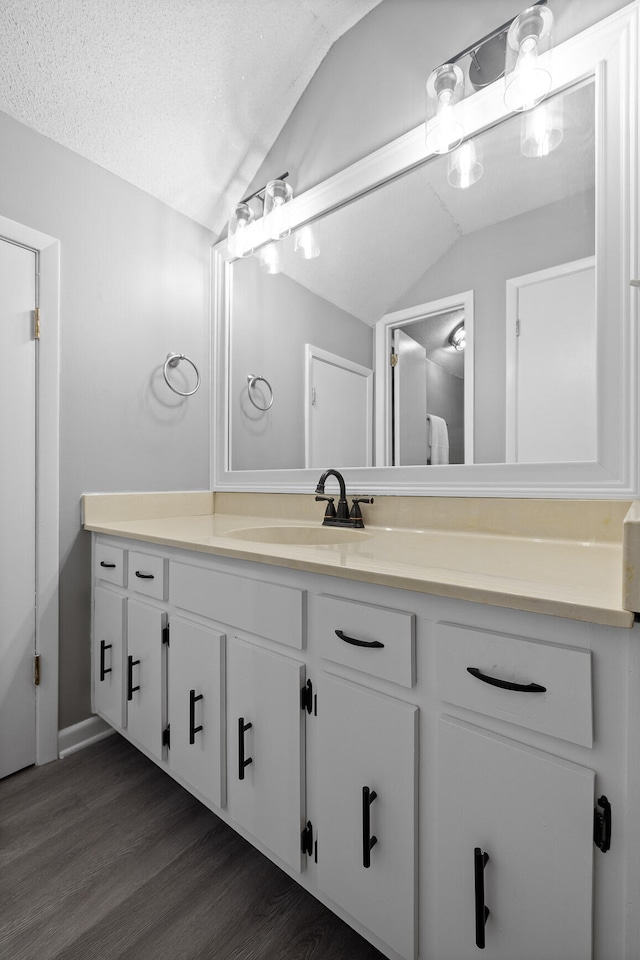 bathroom with vanity, a textured ceiling, vaulted ceiling, and hardwood / wood-style floors