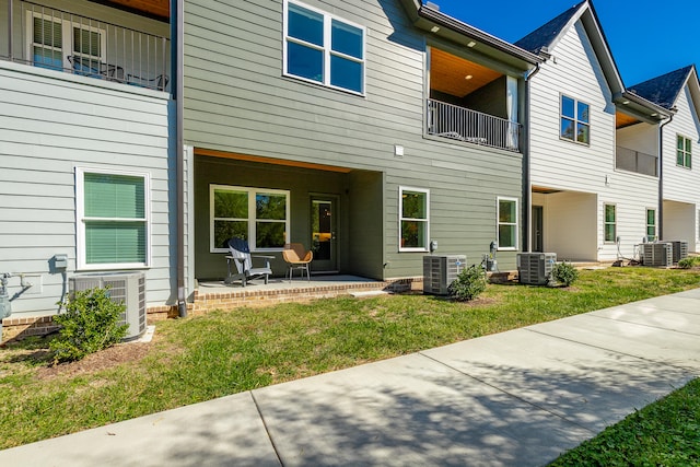 back of house with a balcony, a yard, and central air condition unit