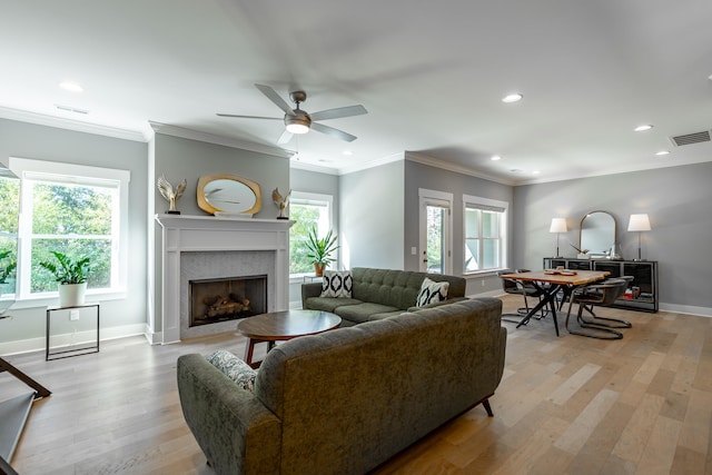 living room with a wealth of natural light, ornamental molding, and light hardwood / wood-style flooring