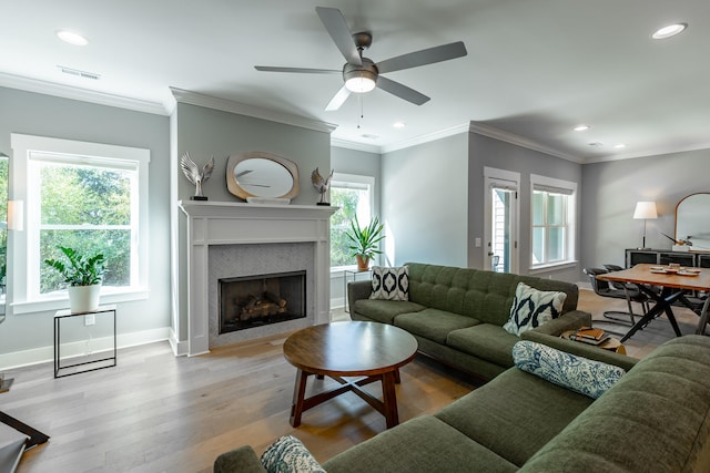 living room featuring ornamental molding, light wood-type flooring, and ceiling fan