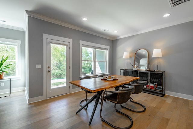 dining room with light hardwood / wood-style floors, crown molding, and a healthy amount of sunlight