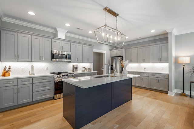 kitchen with gray cabinets, a kitchen island with sink, stainless steel appliances, light hardwood / wood-style floors, and decorative light fixtures