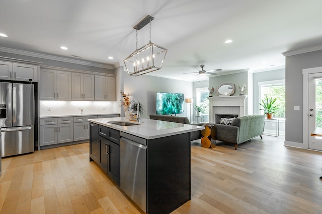 kitchen with appliances with stainless steel finishes, light hardwood / wood-style flooring, an island with sink, and gray cabinets