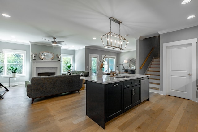 kitchen featuring sink, an island with sink, light hardwood / wood-style flooring, and decorative light fixtures