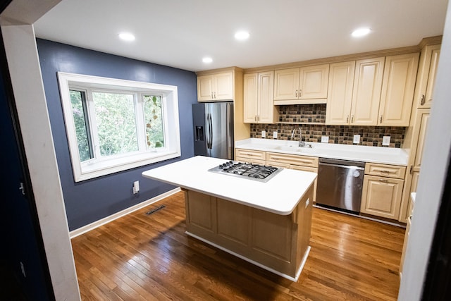 kitchen with sink, stainless steel appliances, dark hardwood / wood-style floors, decorative backsplash, and a kitchen island