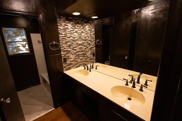 bathroom featuring decorative backsplash, hardwood / wood-style floors, vanity, and a bath