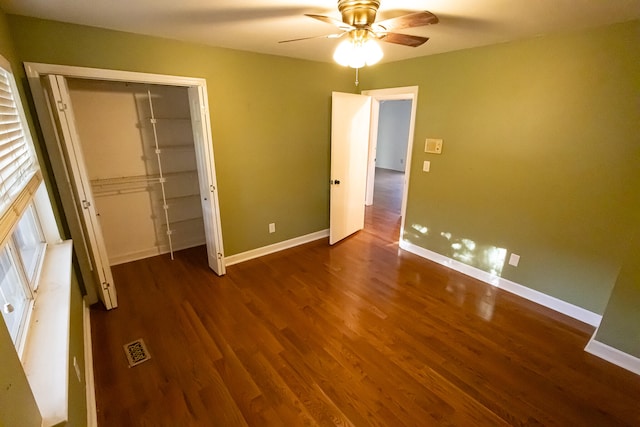 unfurnished bedroom featuring ceiling fan, dark hardwood / wood-style flooring, and a closet