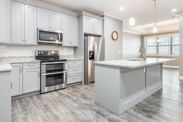 kitchen with light hardwood / wood-style flooring, backsplash, sink, light stone countertops, and appliances with stainless steel finishes