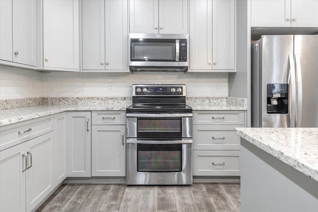 kitchen with light stone counters, stainless steel appliances, and wood-type flooring