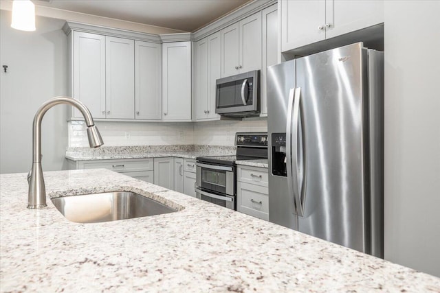 kitchen with light stone counters, sink, appliances with stainless steel finishes, and decorative backsplash