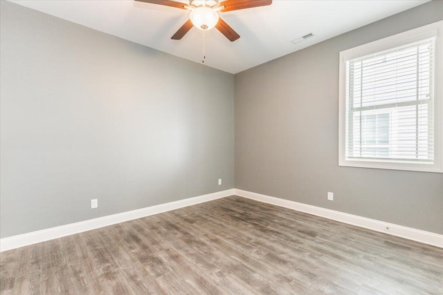 empty room featuring a healthy amount of sunlight, hardwood / wood-style flooring, and ceiling fan