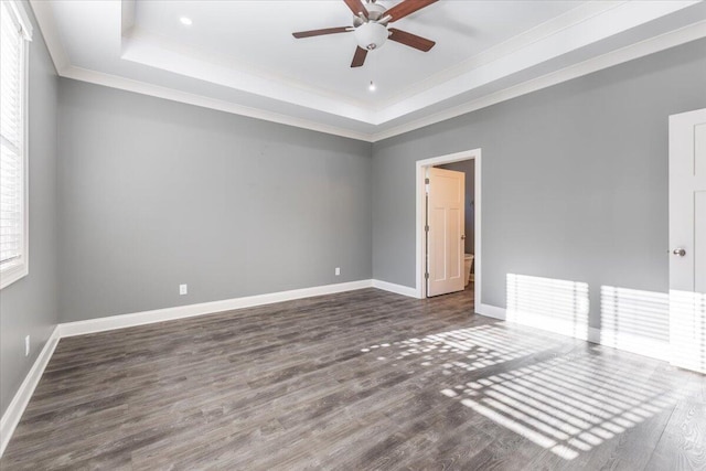 empty room featuring ornamental molding, dark hardwood / wood-style floors, a tray ceiling, and ceiling fan