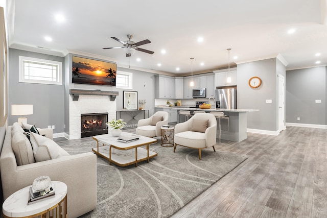 living room with crown molding, light wood-type flooring, and ceiling fan