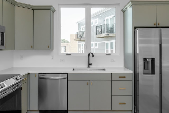 kitchen with sink, appliances with stainless steel finishes, gray cabinetry, and a healthy amount of sunlight