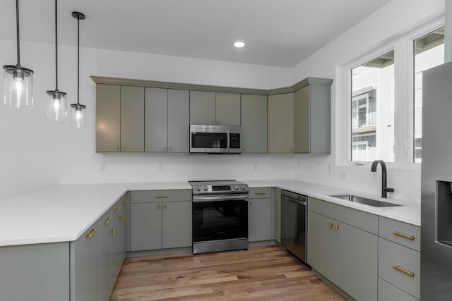 kitchen with sink, pendant lighting, gray cabinets, appliances with stainless steel finishes, and light hardwood / wood-style floors