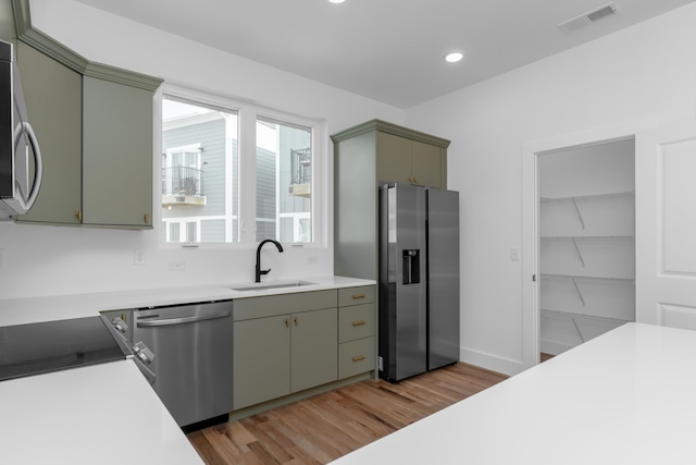 kitchen with appliances with stainless steel finishes, sink, and light wood-type flooring