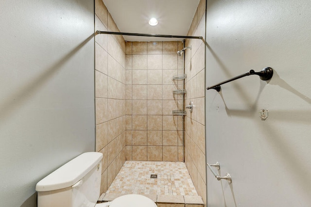 bathroom with toilet and a tile shower