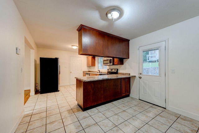 kitchen featuring sink, stainless steel appliances, light tile patterned floors, and kitchen peninsula