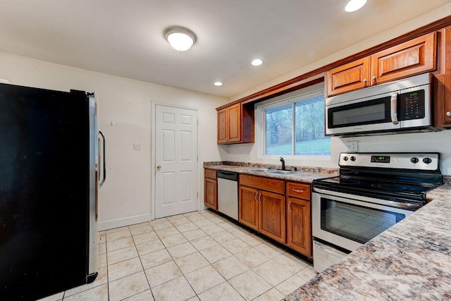 kitchen featuring light stone counters, stainless steel appliances, sink, and light tile patterned flooring