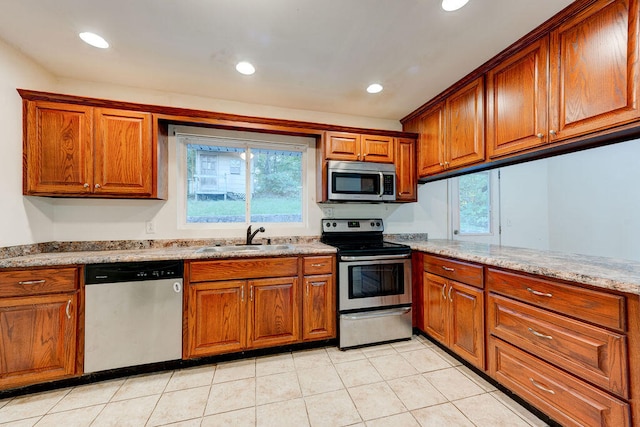 kitchen featuring light stone countertops, light tile patterned flooring, appliances with stainless steel finishes, and sink