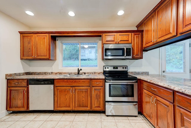 kitchen with light tile patterned flooring, light stone countertops, stainless steel appliances, and sink