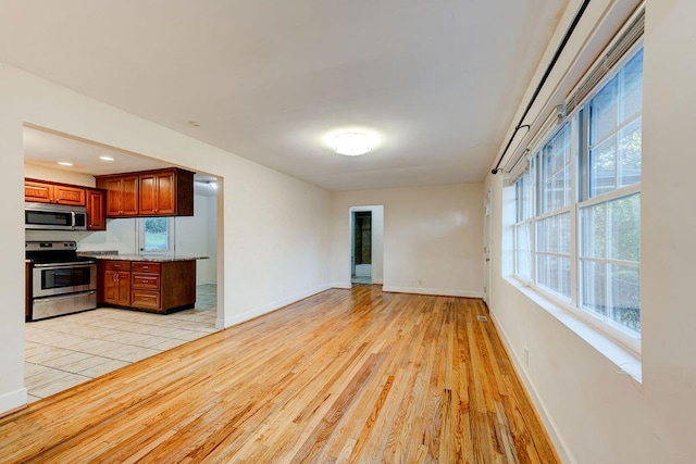 kitchen with light stone countertops, appliances with stainless steel finishes, and light hardwood / wood-style floors