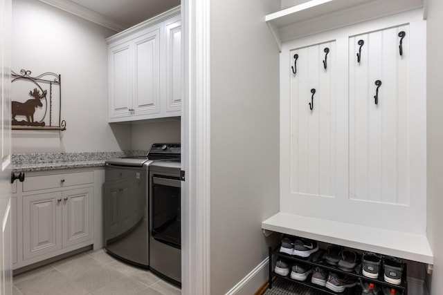 washroom with light tile patterned floors, baseboards, washing machine and clothes dryer, cabinet space, and ornamental molding