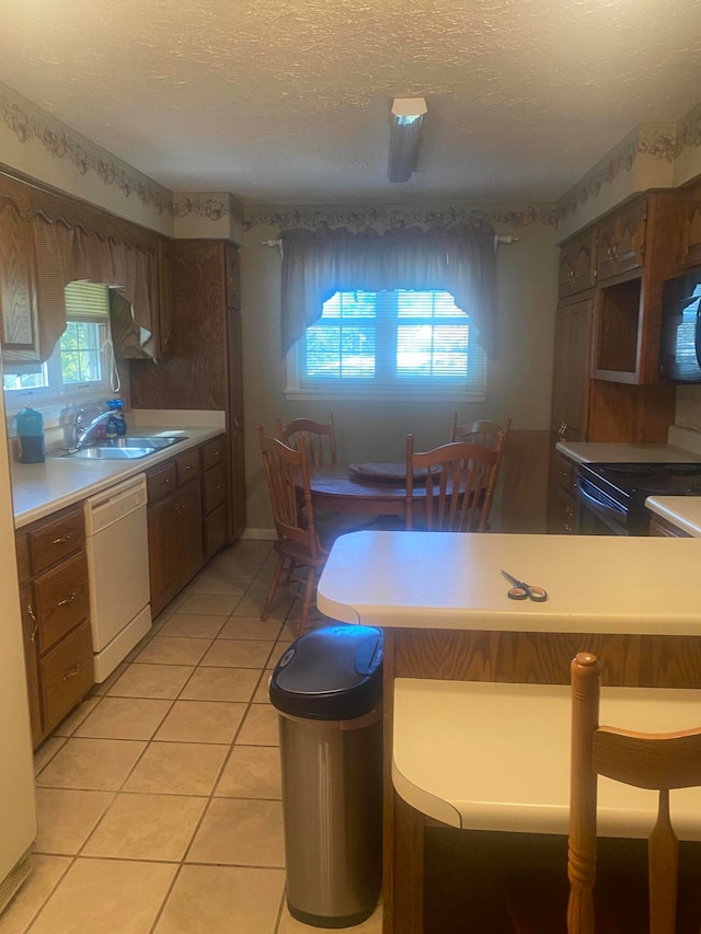 kitchen with a healthy amount of sunlight, black appliances, sink, and a textured ceiling