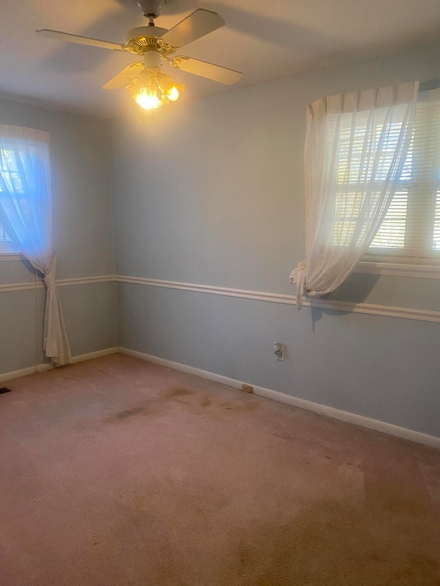 carpeted spare room with ceiling fan and plenty of natural light