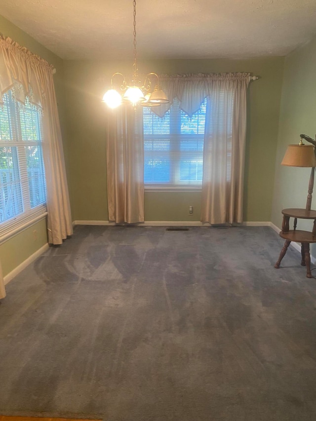 unfurnished dining area featuring a chandelier and dark colored carpet