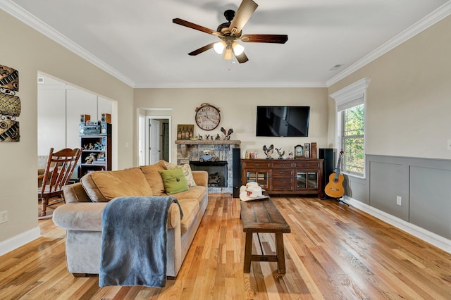 living room featuring ceiling fan, ornamental molding, light hardwood / wood-style flooring, and a fireplace