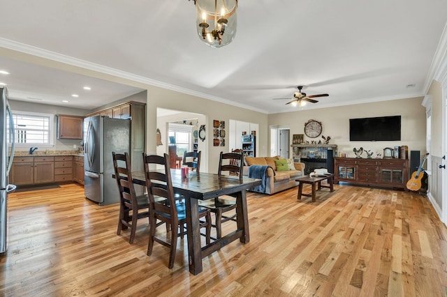 dining area featuring crown molding, light wood-type flooring, and ceiling fan