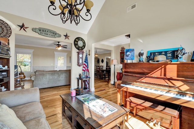 living room with high vaulted ceiling, ornamental molding, ceiling fan with notable chandelier, and light hardwood / wood-style floors