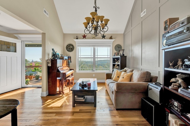 living area with lofted ceiling, crown molding, a notable chandelier, and light wood-type flooring