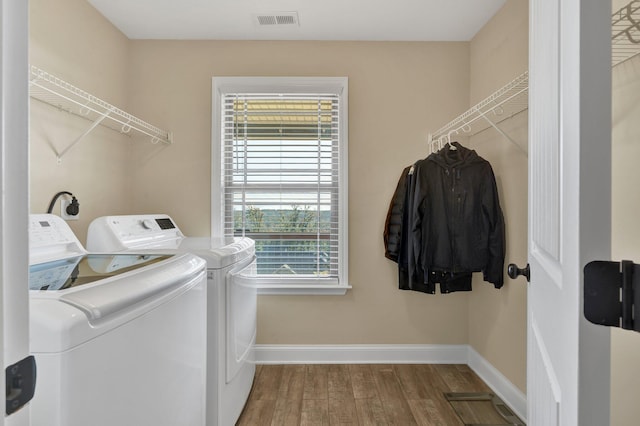 clothes washing area featuring hardwood / wood-style floors and washer and dryer