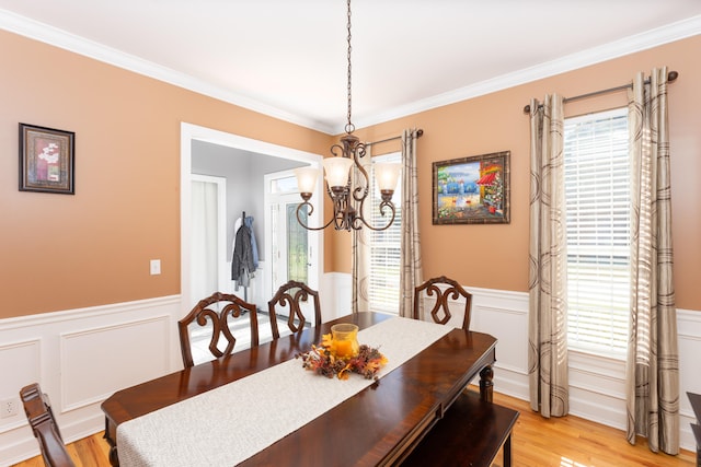 dining space featuring light hardwood / wood-style floors, ornamental molding, and a chandelier