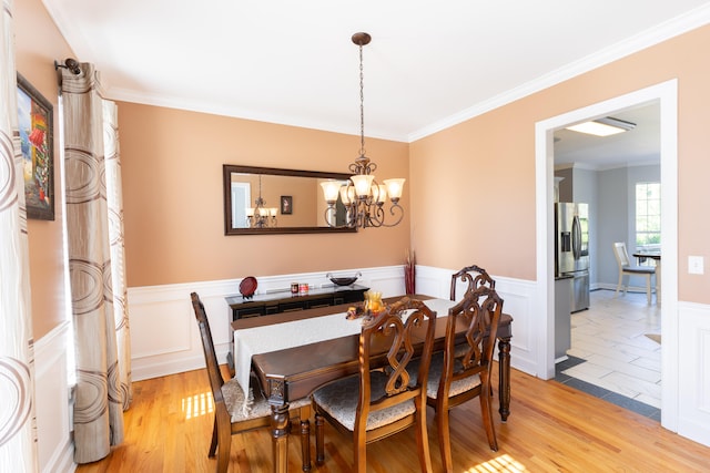 dining area featuring light hardwood / wood-style floors, an inviting chandelier, and ornamental molding