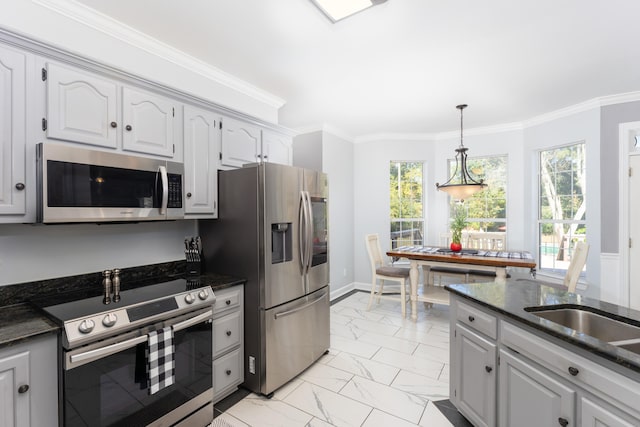 kitchen with dark stone counters, ornamental molding, pendant lighting, white cabinetry, and appliances with stainless steel finishes