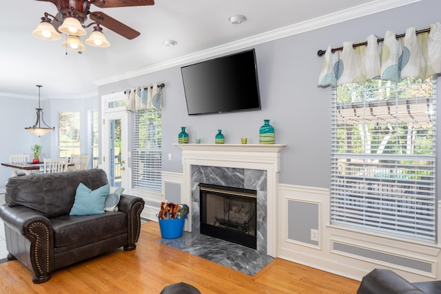 living room with ceiling fan, crown molding, a high end fireplace, and hardwood / wood-style floors